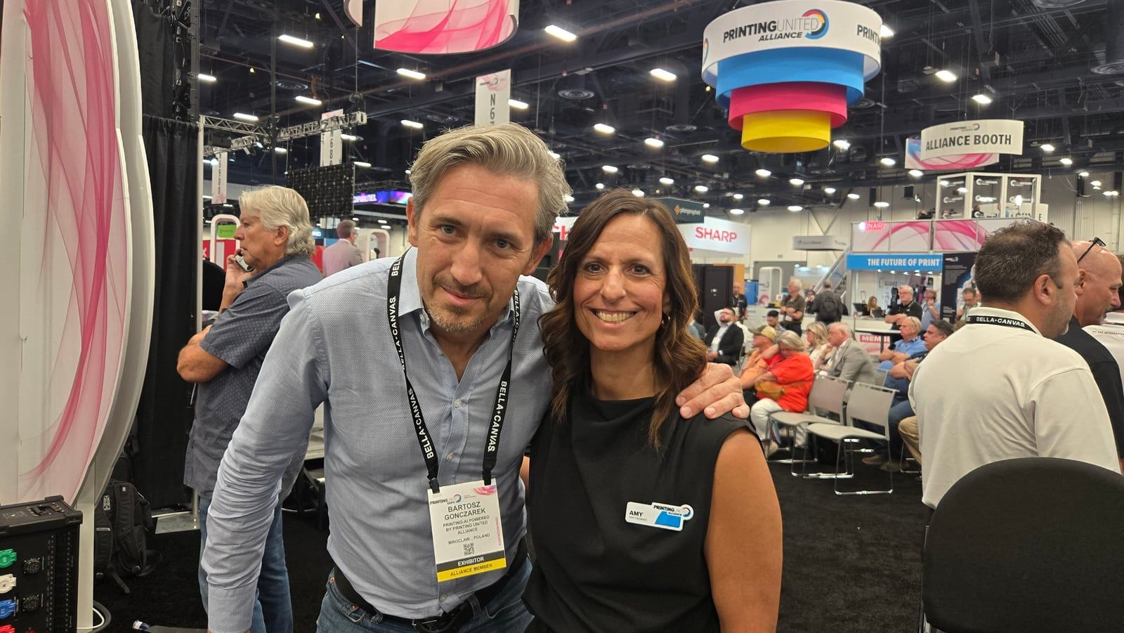 Bartosz Gonczarek with a guest on the Expo floor next to the PRINTING AI pavilion at PRINTING United Expo in Las Vegas