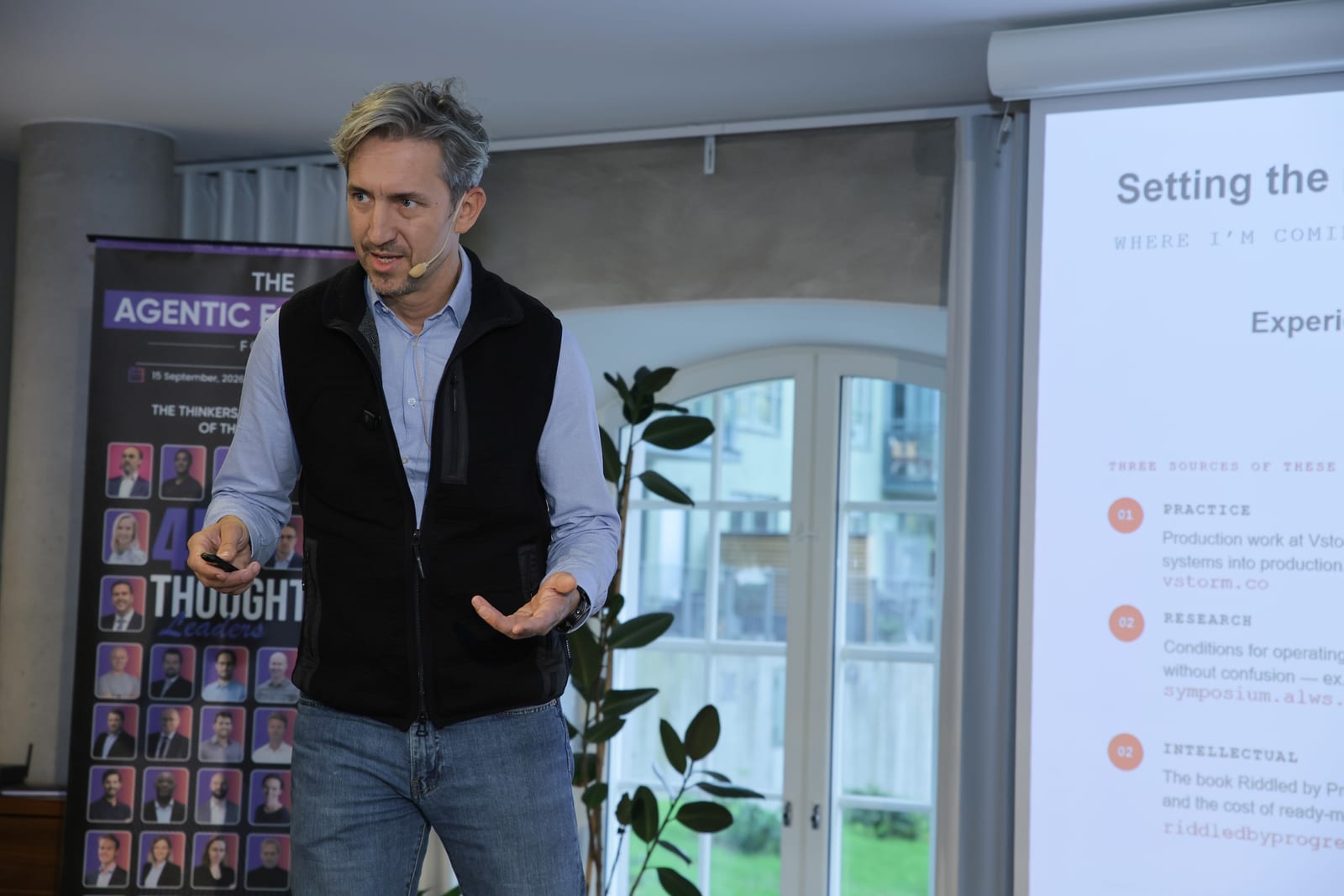 Bartosz Adam Gonczarek speaking on stage at The Agentic Economy Forum in Stockholm, with a slide about practice, research and intellectual sources behind his talk